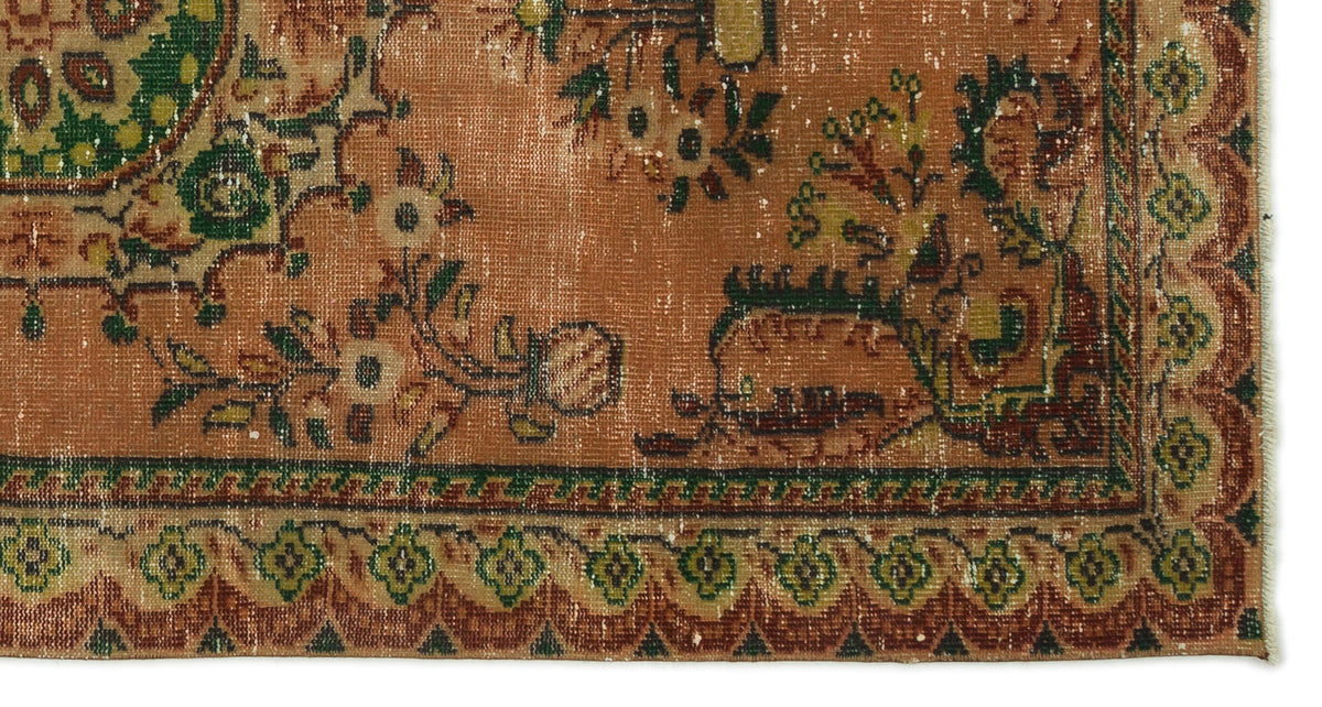 Distressed terracotta rug with a traditional floral medallion pattern, green and cream accents, and a geometric border.