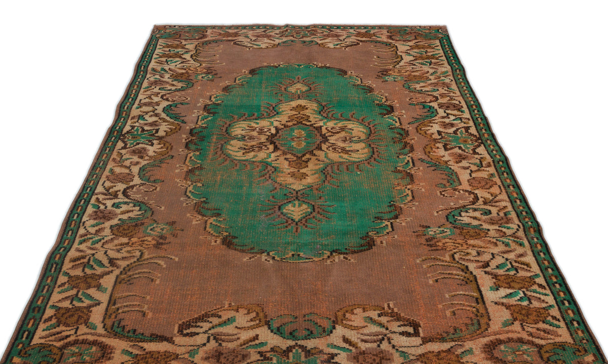 Distressed brown and green vintage-style rug with a central floral medallion and ornate border pattern.