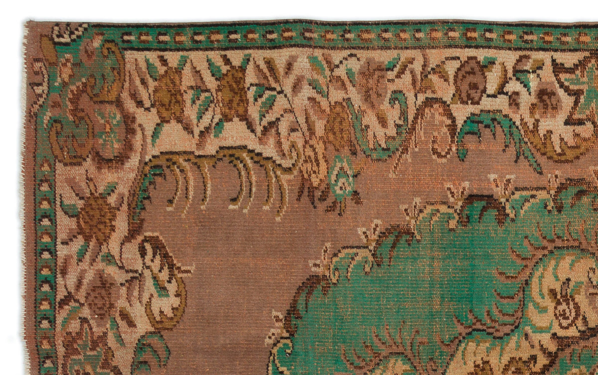 Vintage-style rug fragment with a brown field, green floral medallion, and intricate tan and green border.