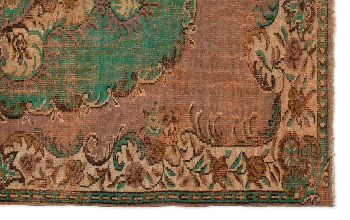Distressed brown and green rug with a traditional floral medallion pattern and a decorative border.