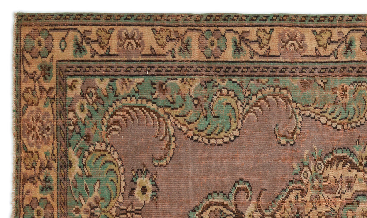 Muted mauve, sage green, and tan rug with a traditional ornate floral border and central paisley-inspired motifs.