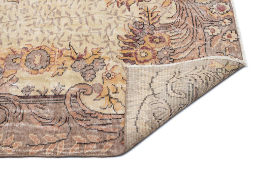 Load image 1 in gallery view. Beige and brown traditional rug with a floral medallion pattern, shown with a corner folded over on a white background.