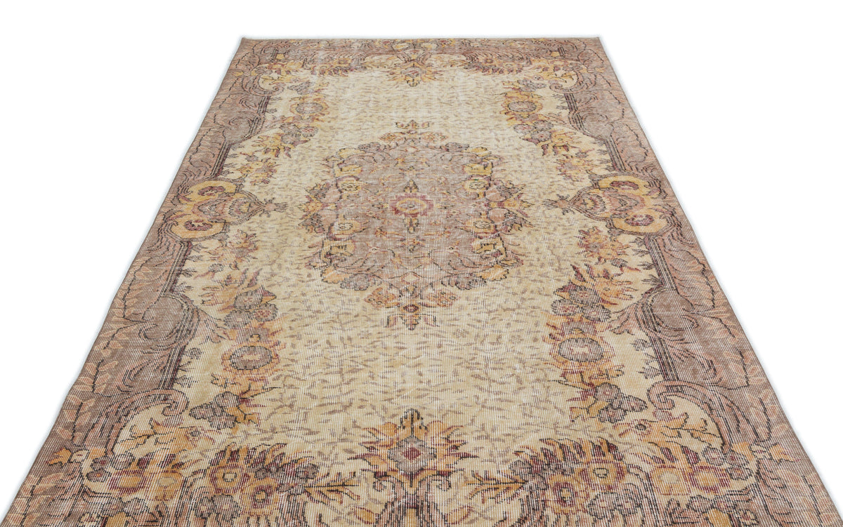 Beige and brown vintage-style rug with a central floral medallion and ornate border on a white background.