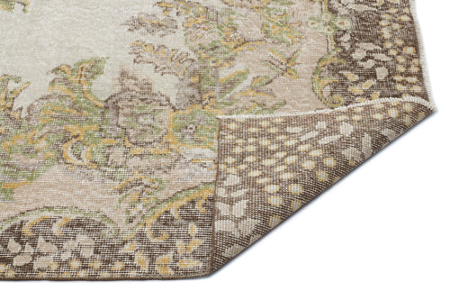 Load image 1 in gallery view. Beige, brown, and sage green floral medallion rug with a folded corner showing the woven backing on a white background.