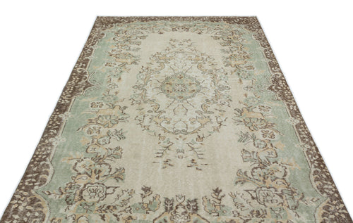 Load image 1 in gallery view. Distressed cream, sage green, and brown rug with a traditional floral medallion pattern and ornate border.