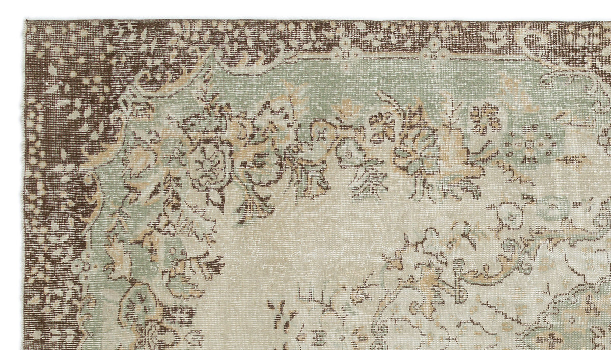 Distressed vintage-style rug with a brown, sage green, and cream floral medallion pattern.