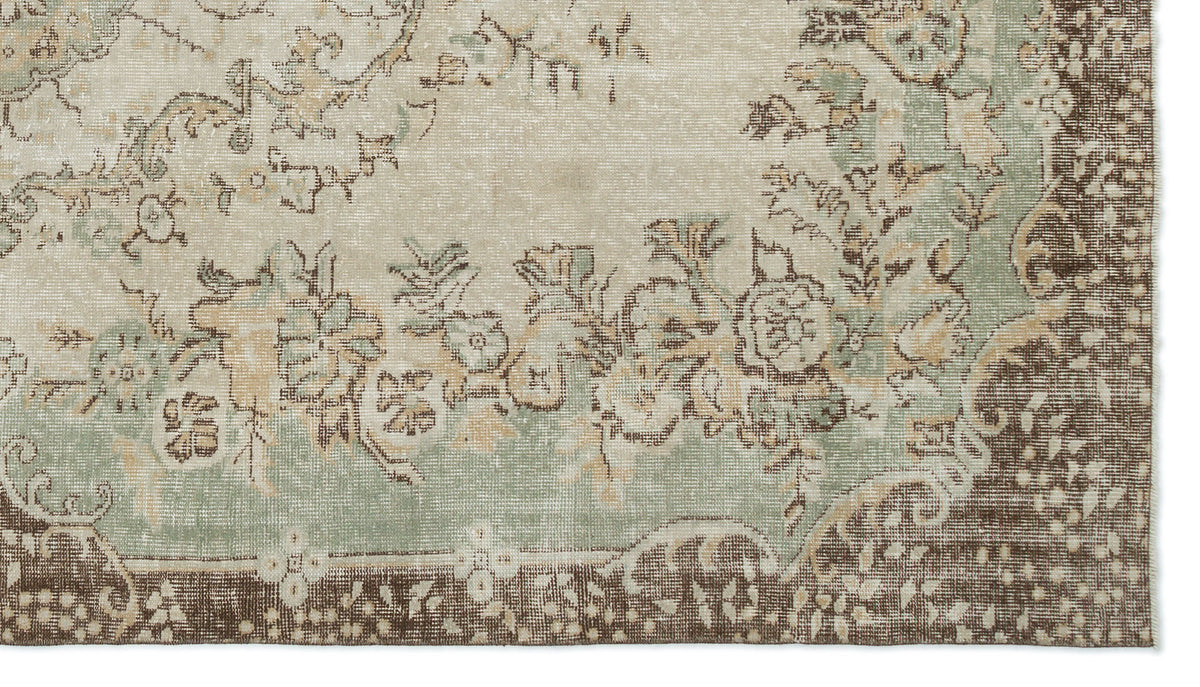 Distressed beige, sage green, and brown rug with a traditional floral medallion pattern and ornate border.