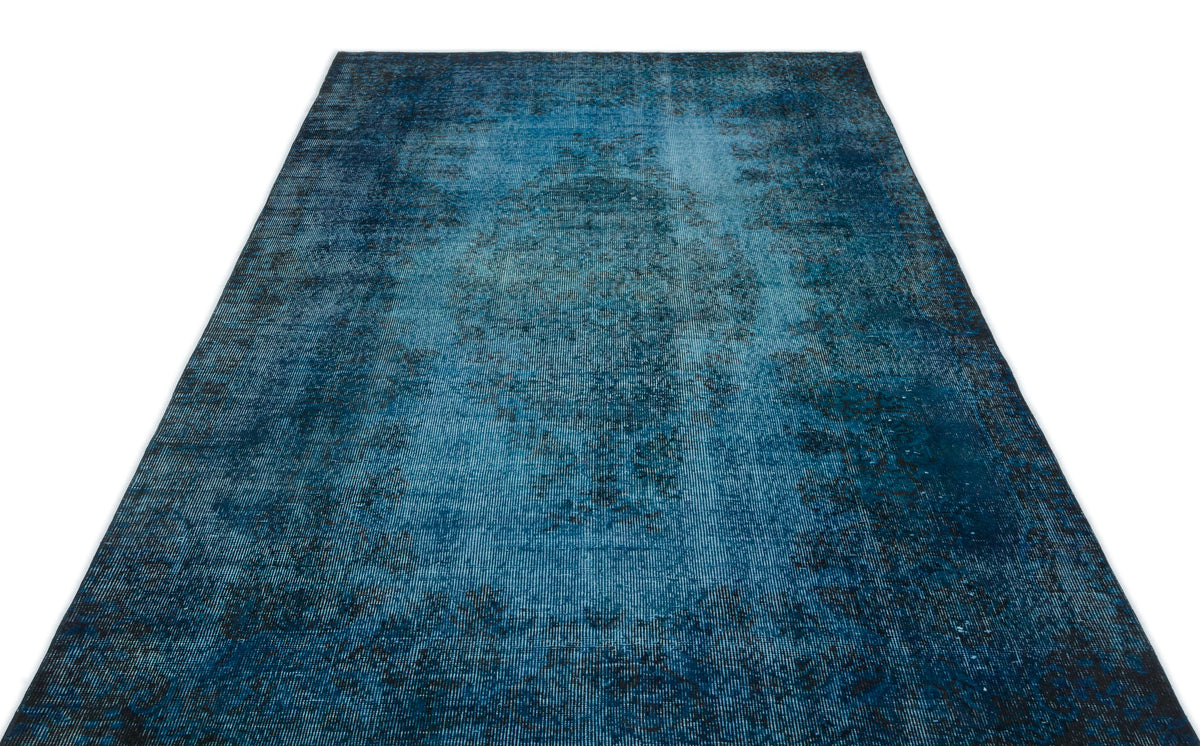 Deep blue distressed area rug with a faded traditional medallion pattern on a white background.