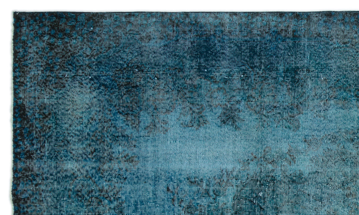 Teal and black distressed overdyed rug with a faded, abstract texture.