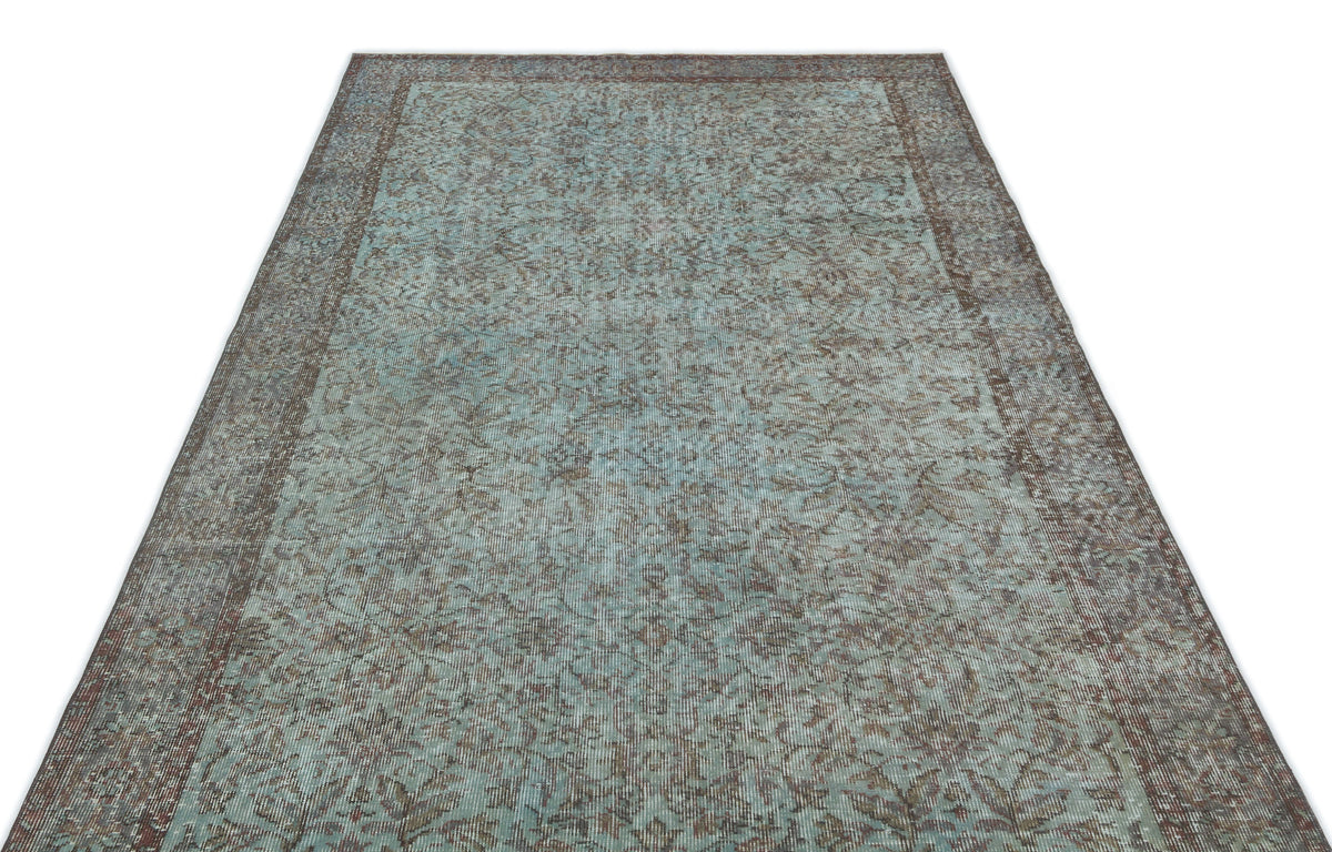 Distressed teal and brown vintage-style rug with an intricate floral pattern and a wide border.