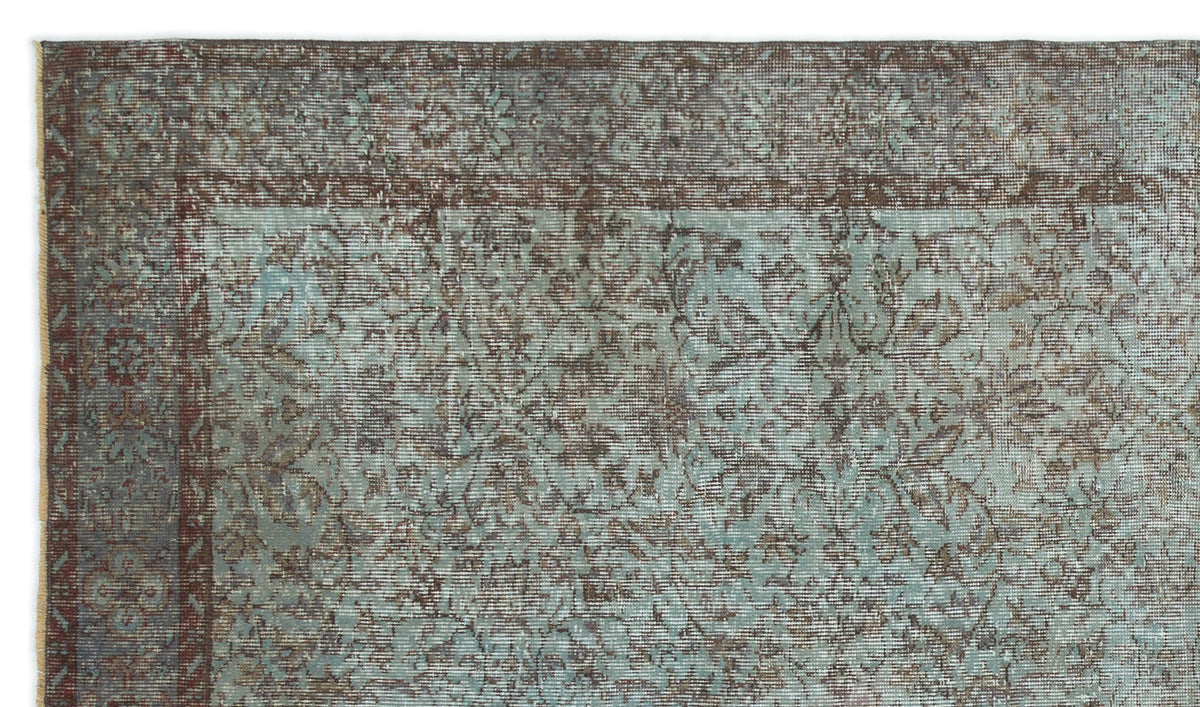 Distressed teal and brown rug with a traditional floral medallion border and intricate vine pattern.