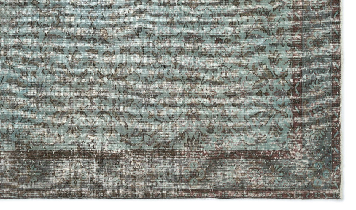 Distressed teal and brown rug with a traditional floral medallion pattern and a wide, ornate border.