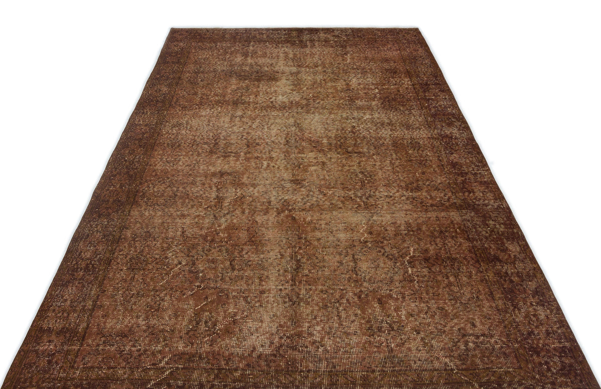 Distressed brown vintage-style rug with a faded traditional border and central medallion pattern on a white background.