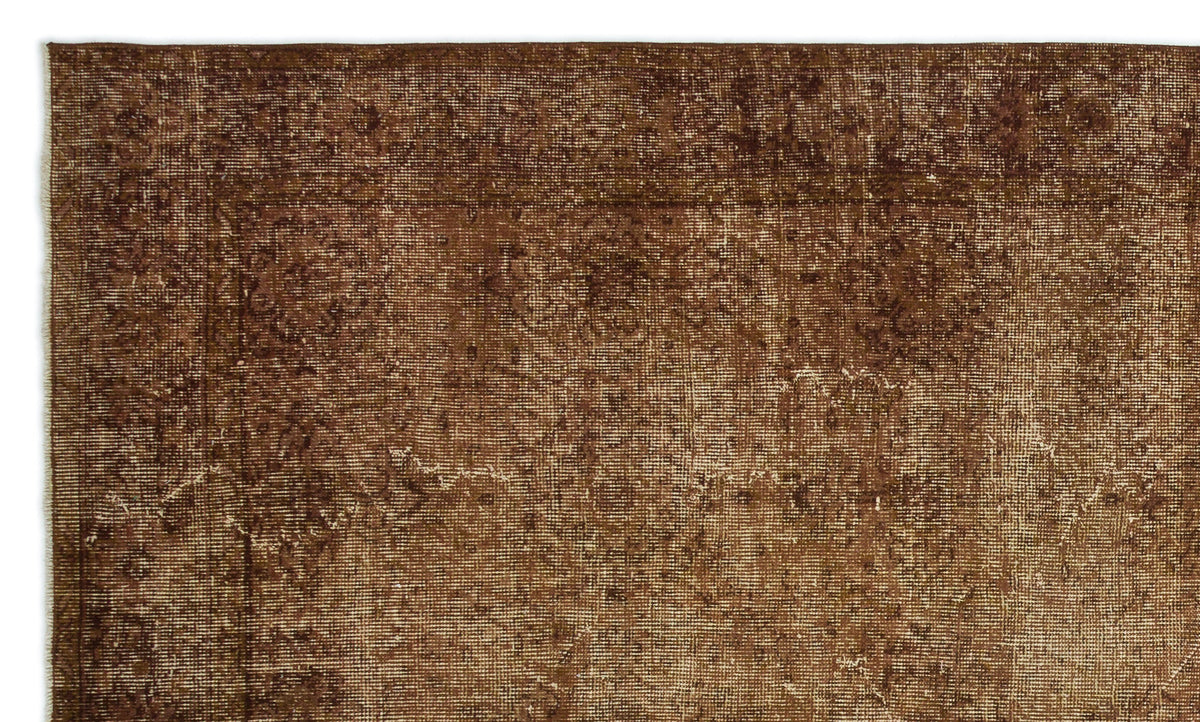 Dark brown distressed rug with a faded traditional border and subtle, worn-in medallion pattern.