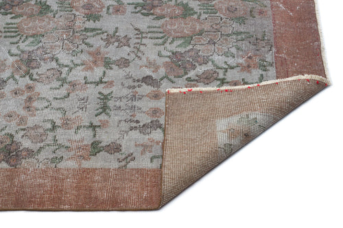 Load image 1 in gallery view. Distressed grey rug with a faded floral pattern and terracotta border, shown with a corner folded over on white background.
