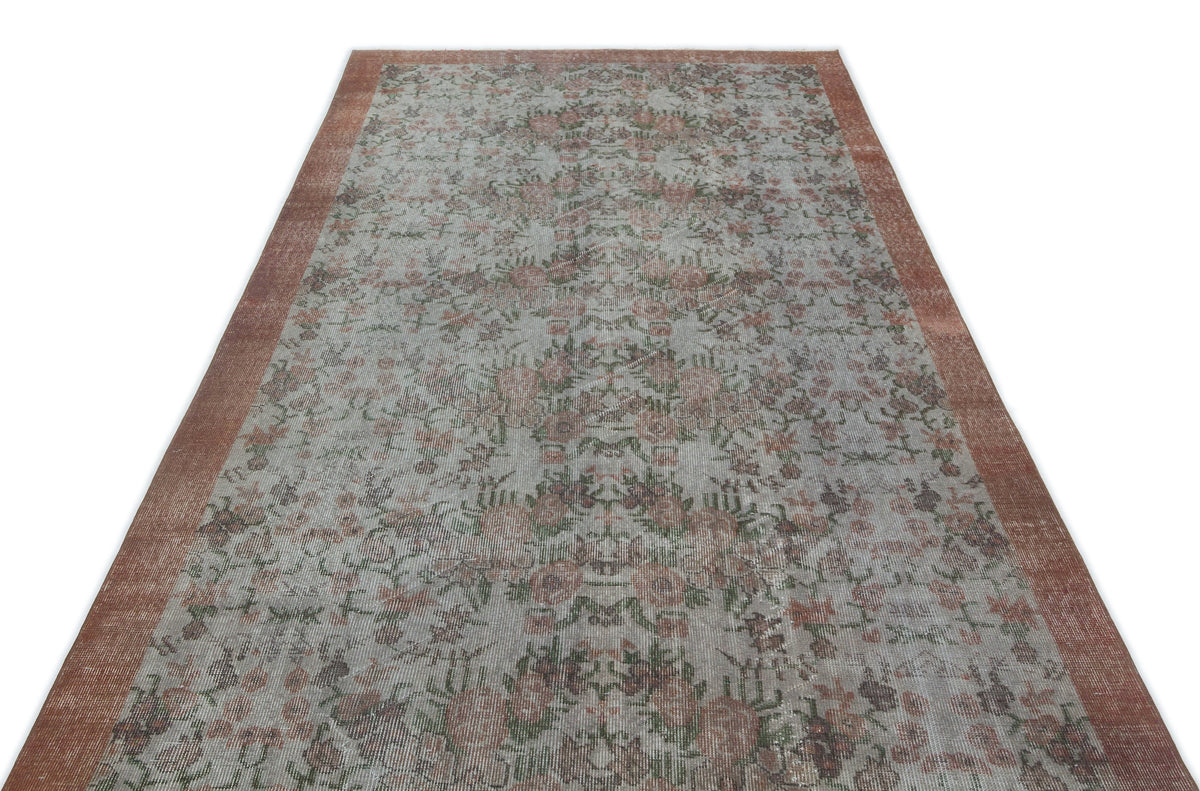 Distressed grey and terracotta rug with a faded floral medallion pattern and a solid terracotta border.