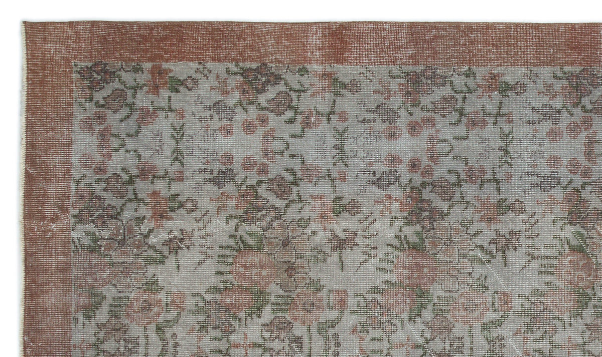 Distressed grey rug with a faded floral pattern and a wide terracotta border.