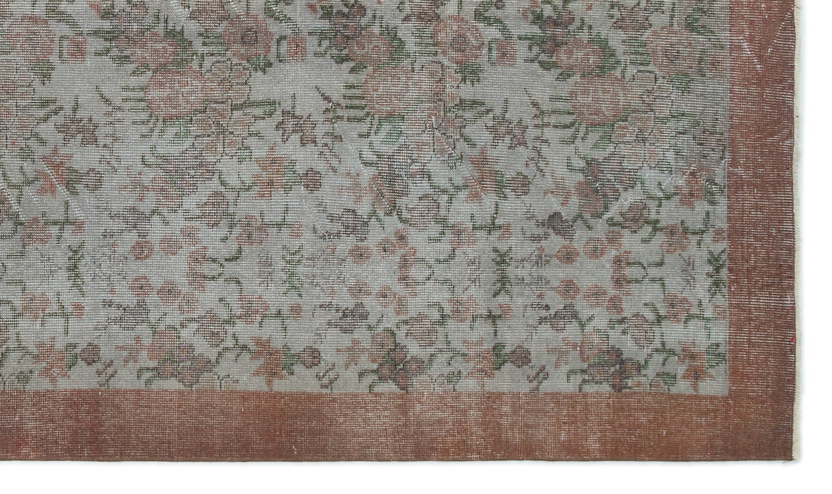 Distressed grey rug with a faded floral pattern in muted pink and green, featuring a solid terracotta border.