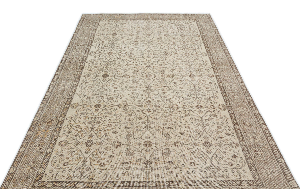 Beige and brown vintage-style rug with a distressed floral medallion pattern and a wide decorative border.