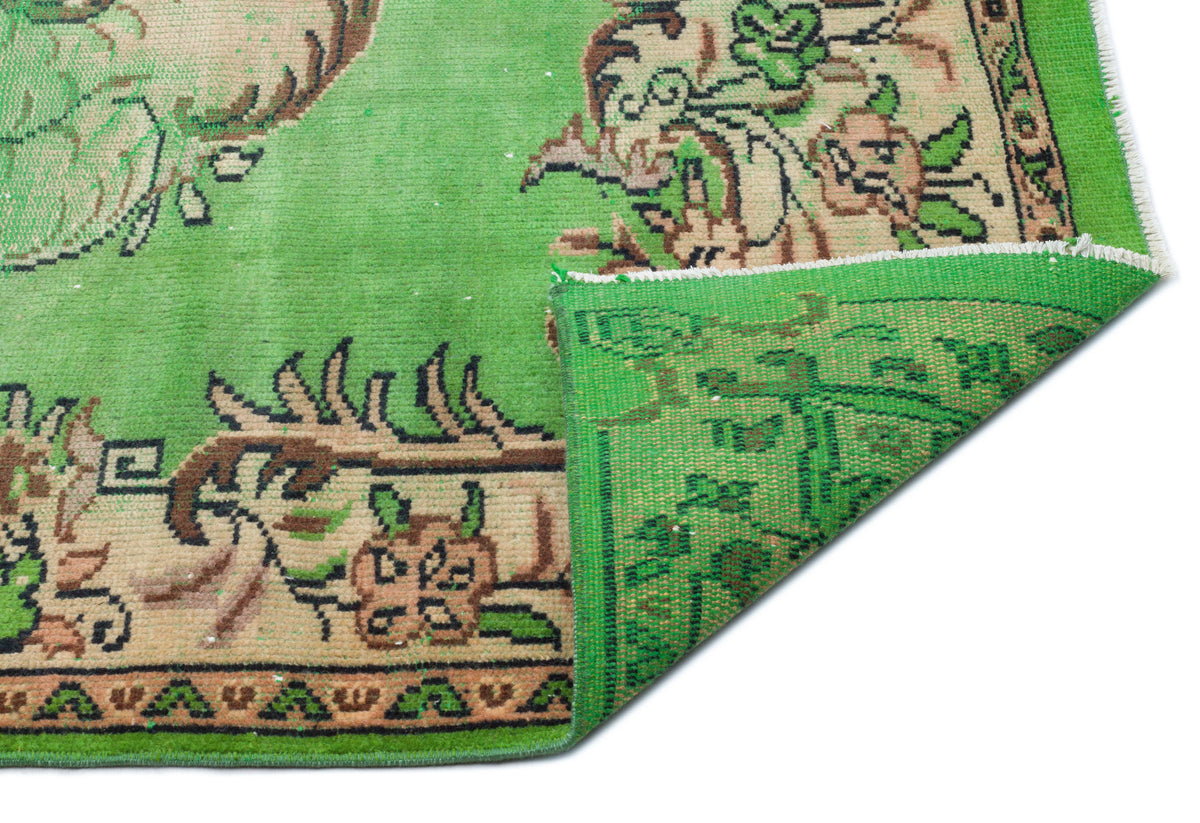 Bright green vintage-style rug with tan and black floral border patterns, shown with a corner folded over.