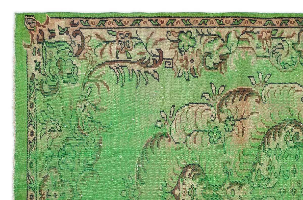 Bright green vintage rug with a brown and black floral border and central botanical motif on a white background.