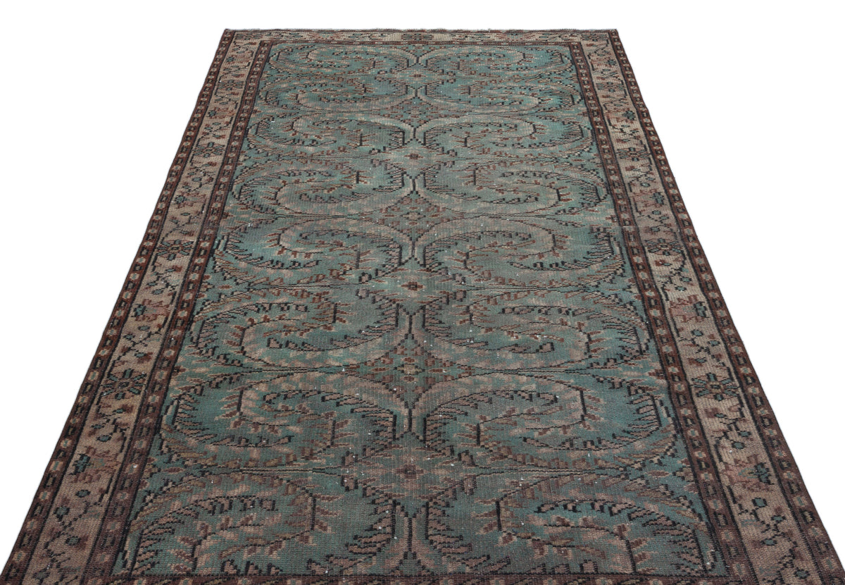 Teal and brown vintage-style rug with a repeating ornate floral medallion pattern and a decorative border.