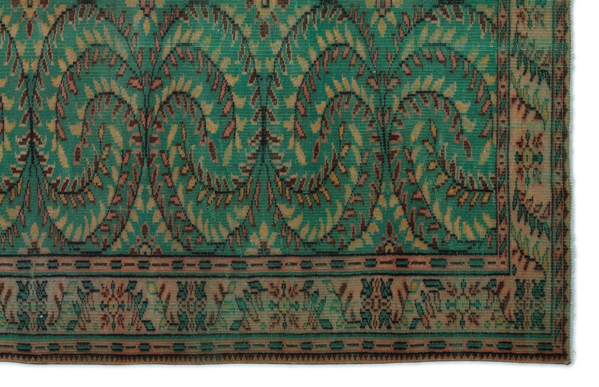 Emerald green rug with a repeating arched leaf pattern in brown and tan, featuring a decorative geometric border.