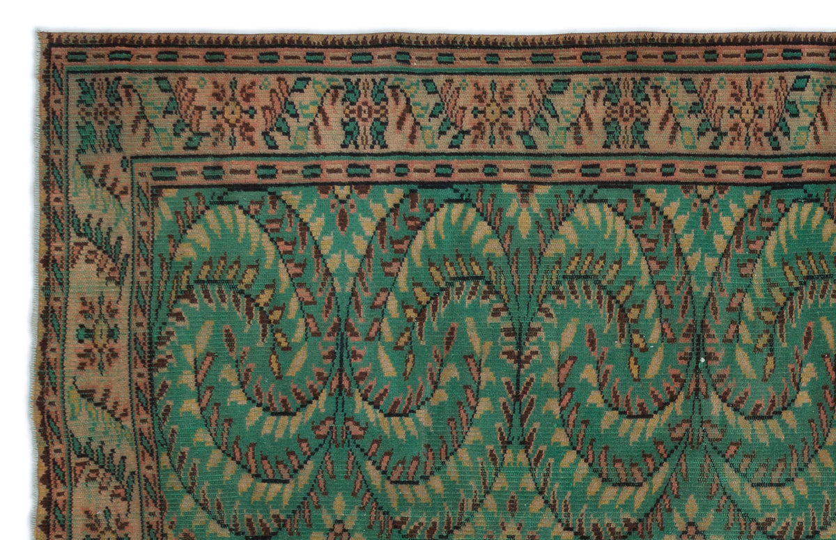 Green and tan vintage-style rug with a repeating paisley-inspired leaf pattern and a decorative floral border.