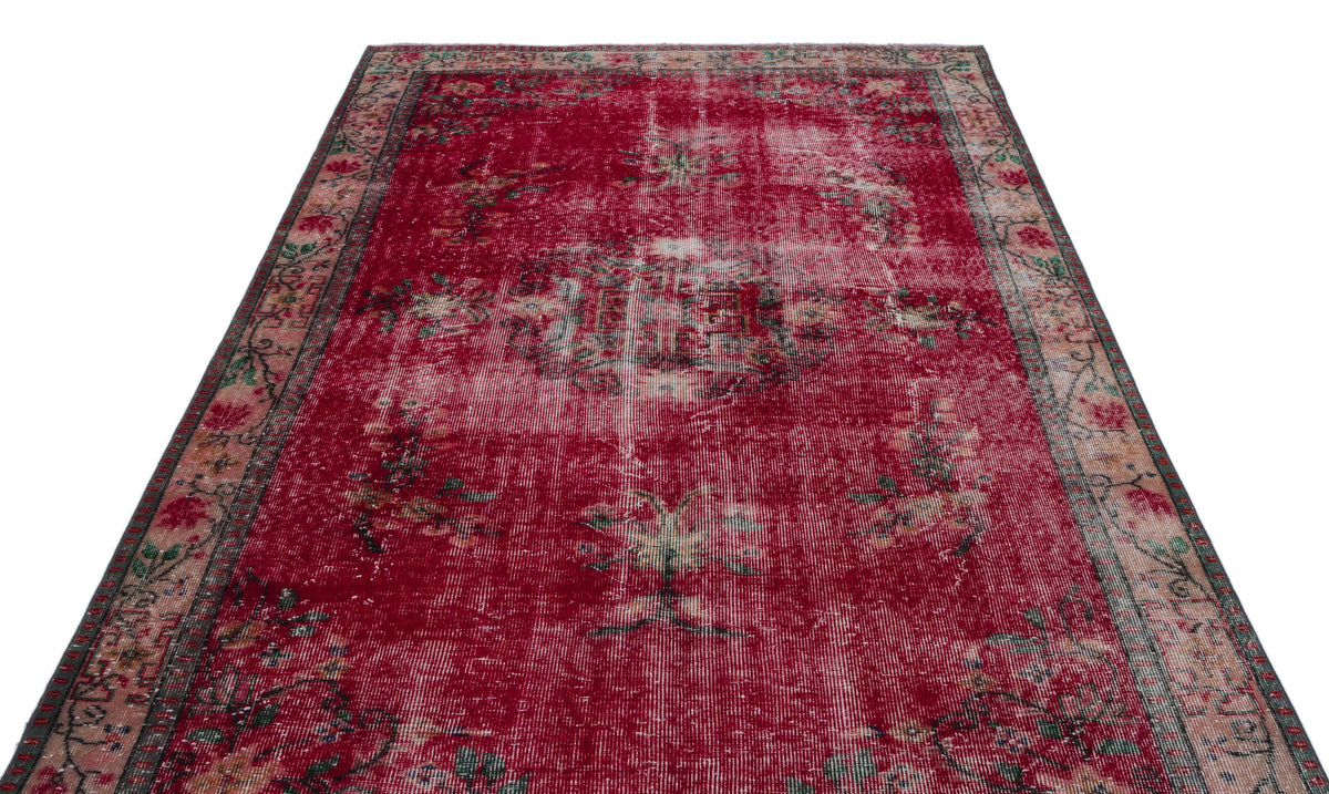 Distressed red rug with a faded central medallion and floral border on a white background.