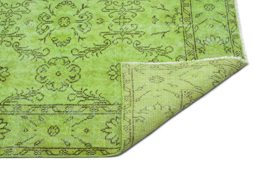 Load image 1 in gallery view. Bright lime green rug with a distressed dark olive floral medallion pattern and a folded corner on a white background.