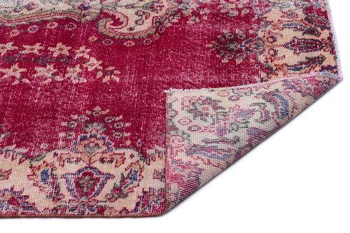 Load image 1 in gallery view. Distressed crimson and beige rug with a traditional floral medallion pattern, shown with a corner folded over.