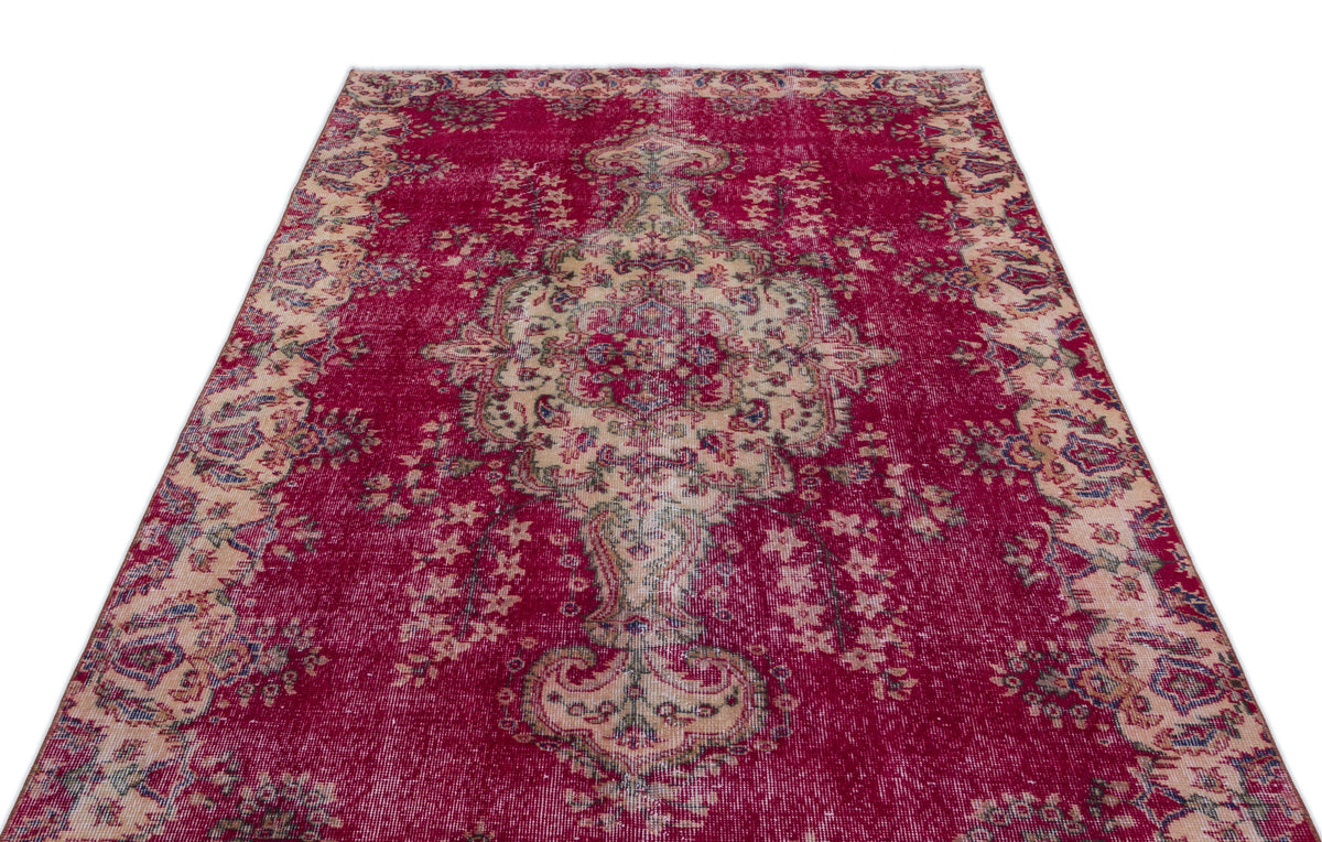 Deep red vintage-style rug with a distressed central medallion and ornate floral border on a white background.