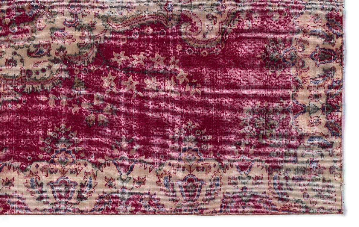 Deep red and beige vintage-style rug with a distressed floral medallion pattern.