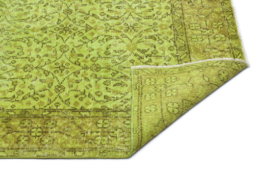 Load image 1 in gallery view. Chartreuse and olive green vintage-style rug with a distressed floral medallion pattern and a folded corner.