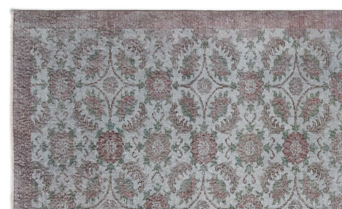 Distressed grey, muted red, and sage green rug with a repeating floral medallion pattern and a solid border.