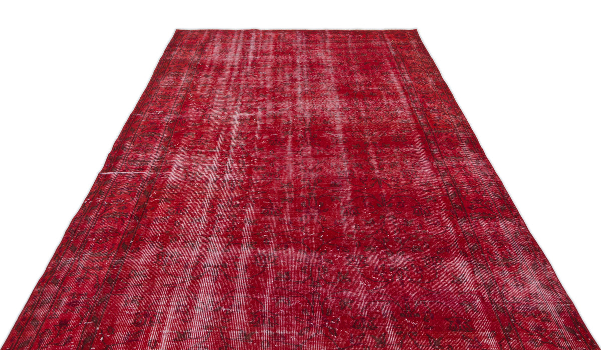 Distressed red vintage rug with a faded traditional floral pattern and white vertical wear lines.