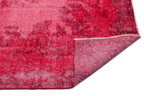 Load image 1 in gallery view. Distressed crimson and magenta rug with a faded floral pattern, shown with a corner folded over on a white background.