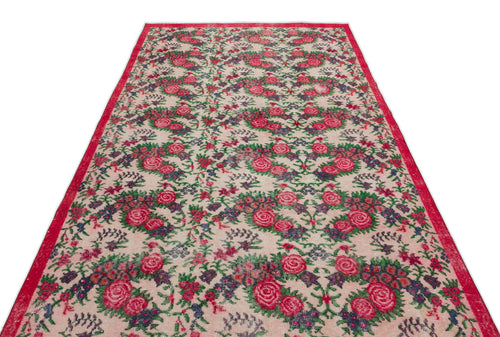 Load image 1 in gallery view. Beige rug with a red border and a repeating floral pattern in shades of pink, green, and dark blue.