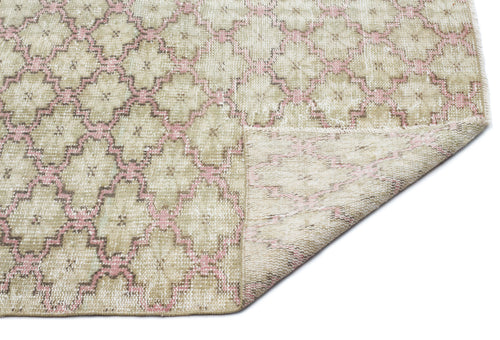 Load image 1 in gallery view. Beige and pink distressed rug with a geometric lattice pattern, shown with a corner folded over on a white background.