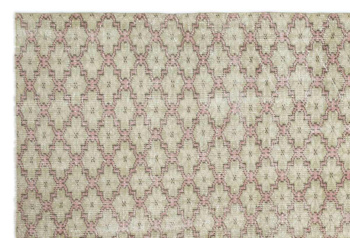 Beige and pink vintage-style rug with a repeating geometric diamond lattice pattern.