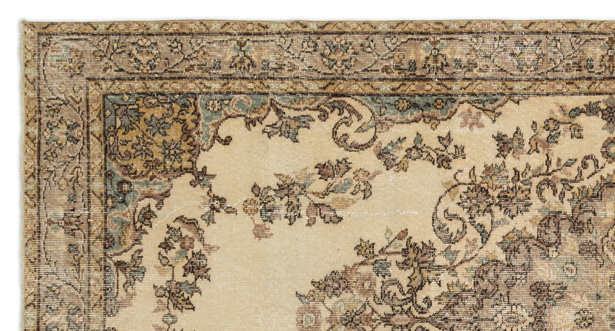 Beige traditional rug with a distressed floral border and central medallion pattern in muted blue, brown, and tan.