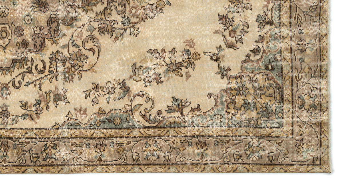 Beige traditional rug with a distressed floral medallion pattern in muted brown, blue, and cream tones.
