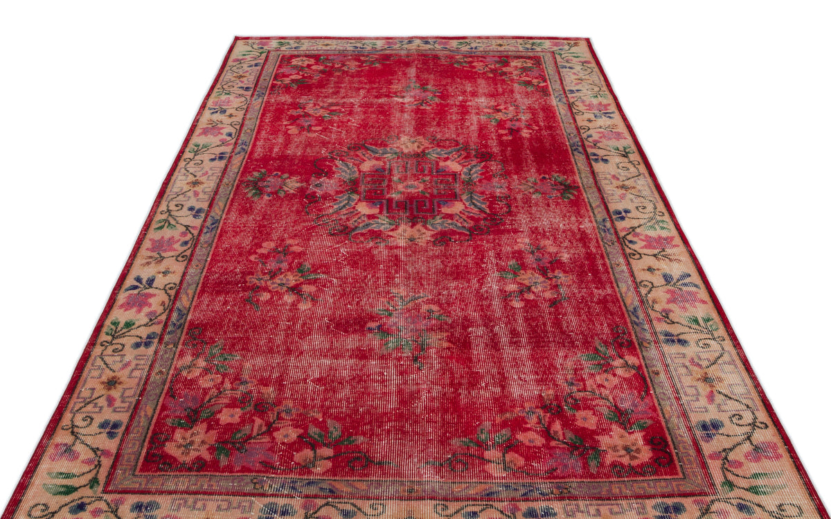 Distressed red vintage rug with a central floral medallion and a beige floral border on a white background.