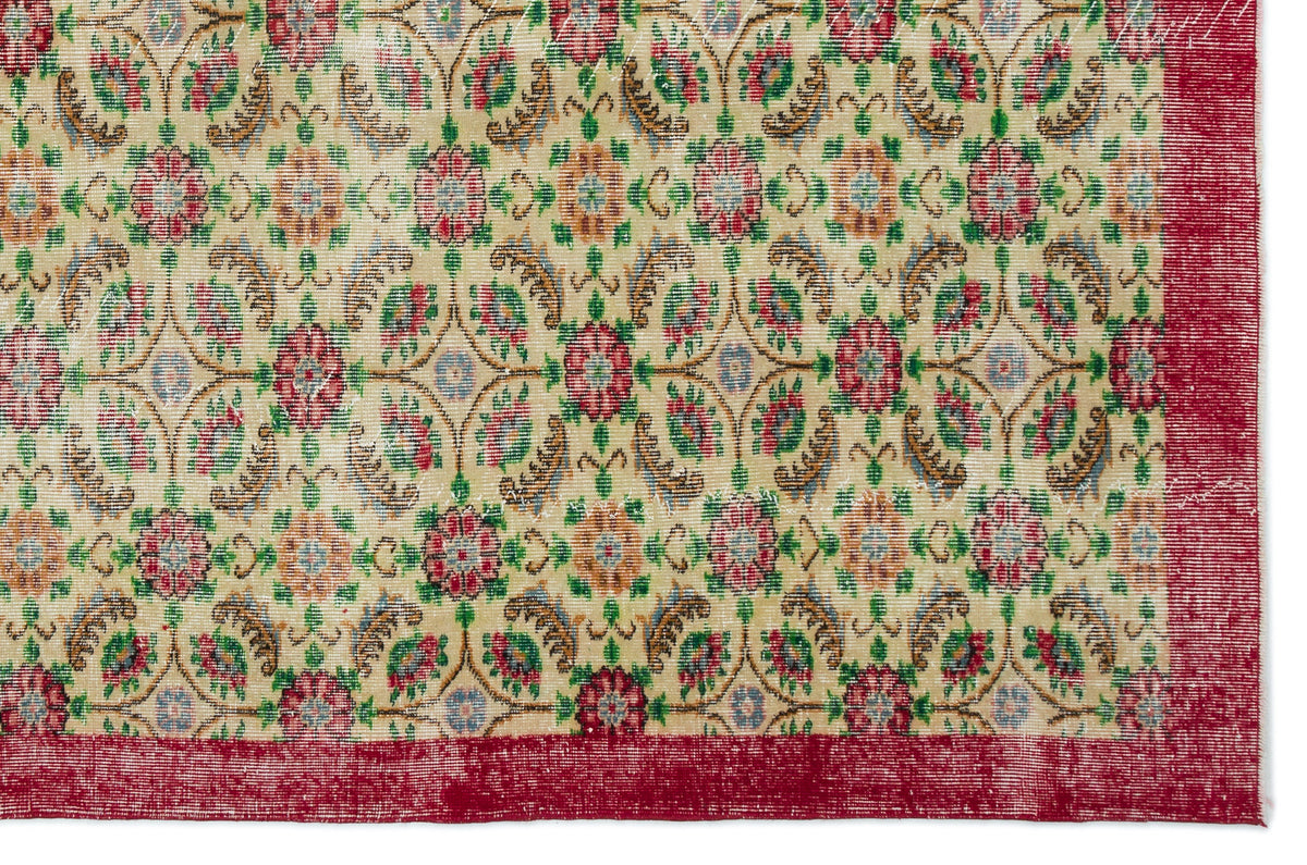 Beige rug with a repeating floral medallion pattern in red, green, and gold, featuring a solid red border.