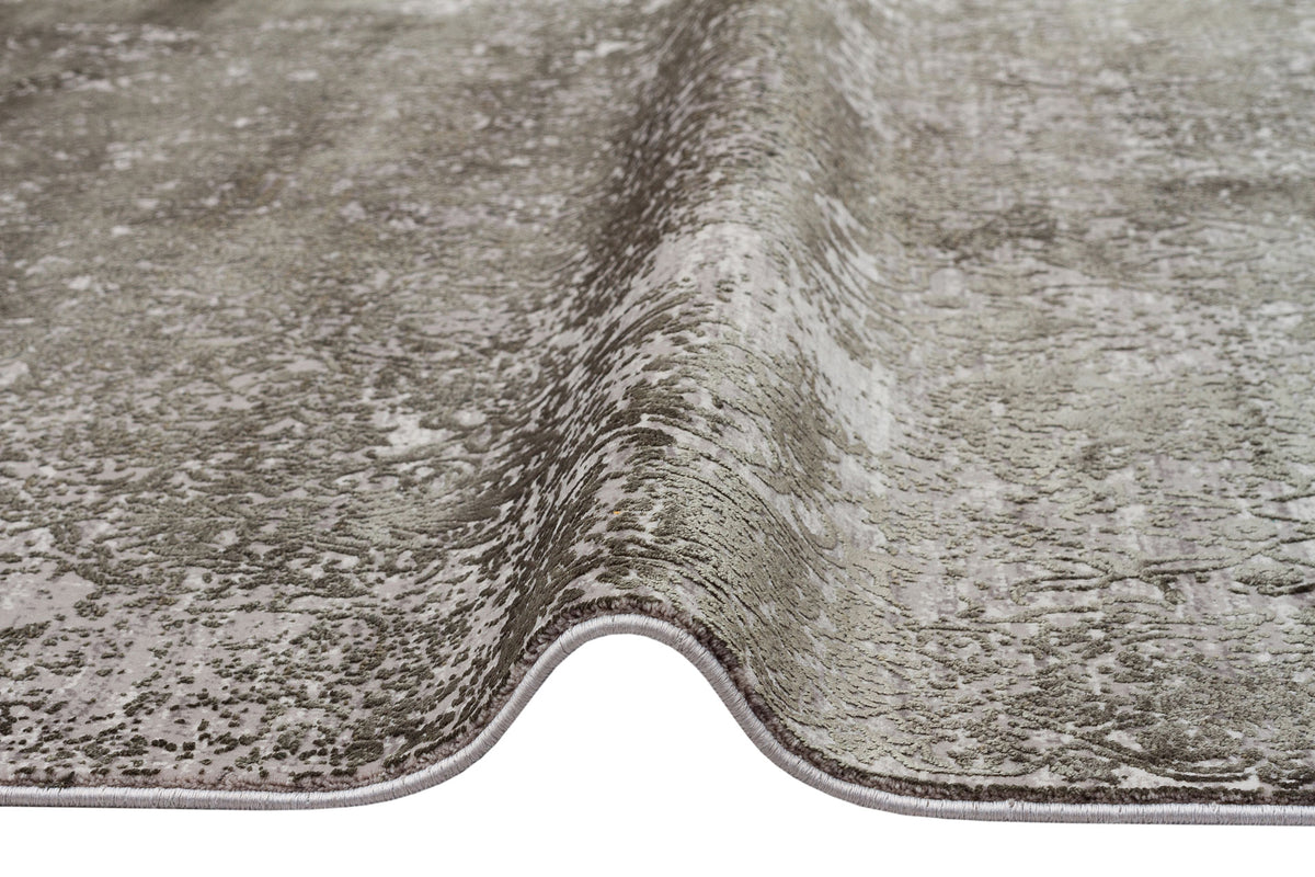 Grey and silver distressed area rug with a textured, abstract pattern and finished serged edges.