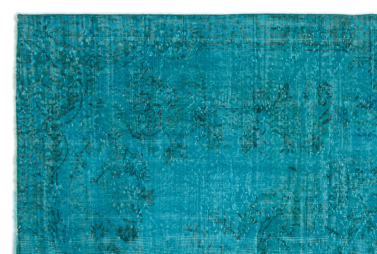 Teal vintage-style rug with a distressed, faded floral pattern and dark blue line details.