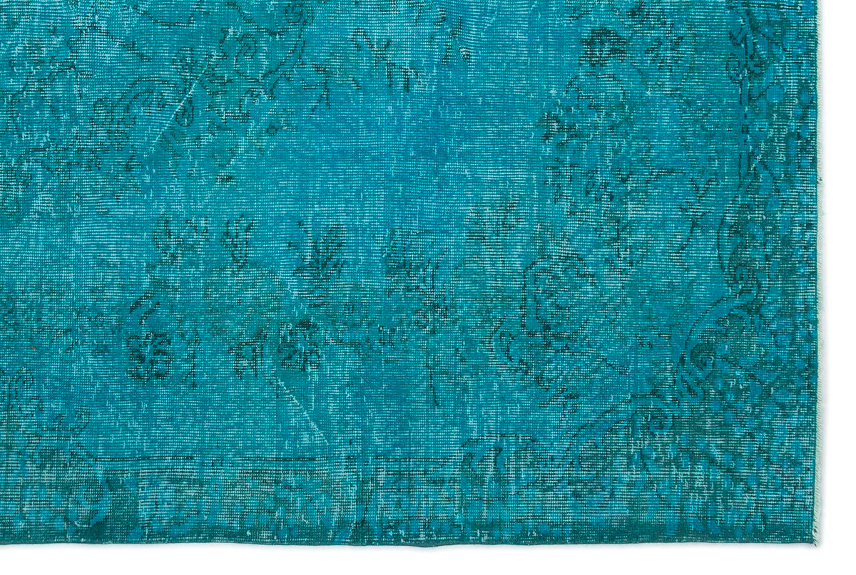 Teal distressed rug with a faded traditional floral pattern on a white background.