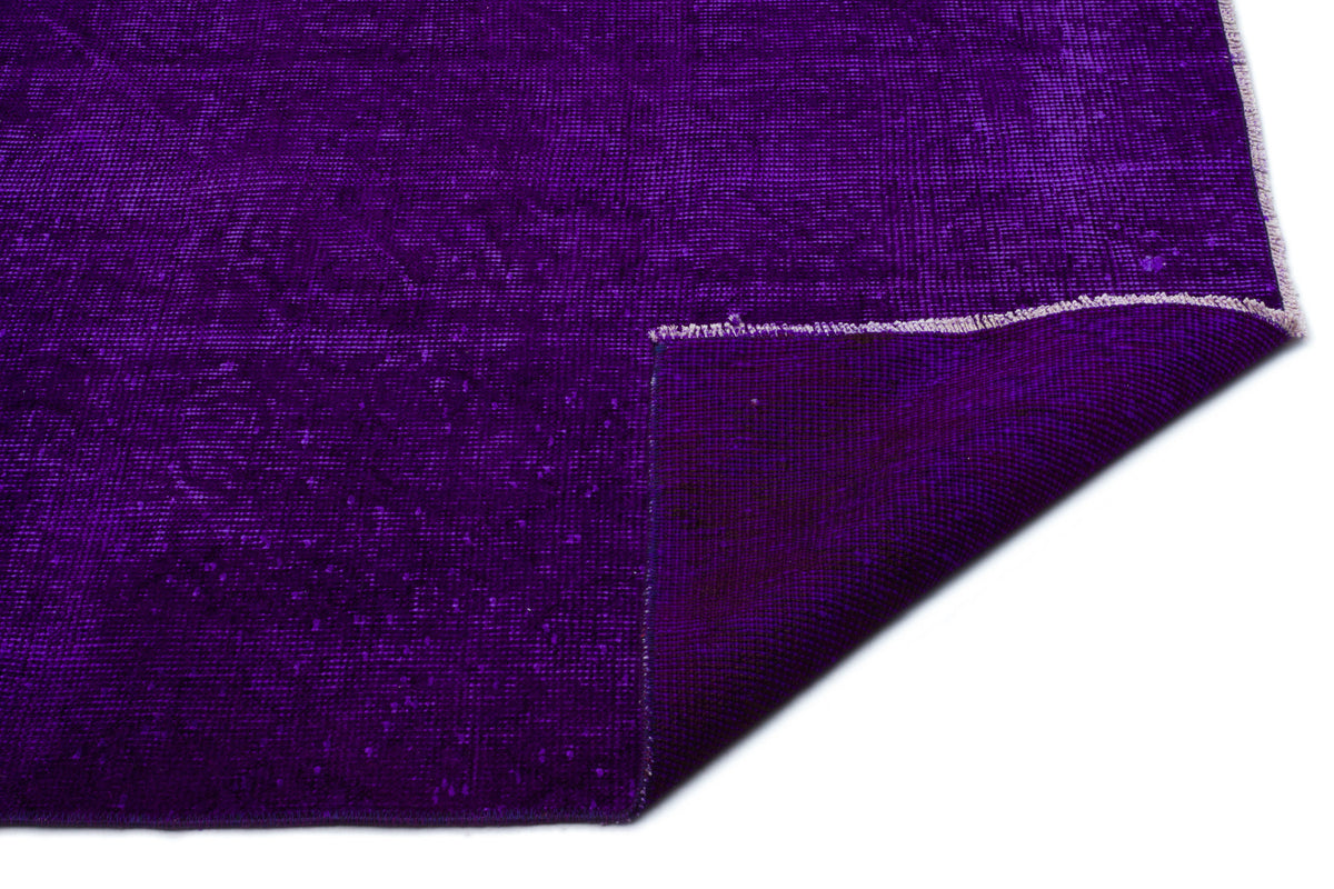 Deep purple distressed-style rug with a folded corner revealing the woven backing on a white background.