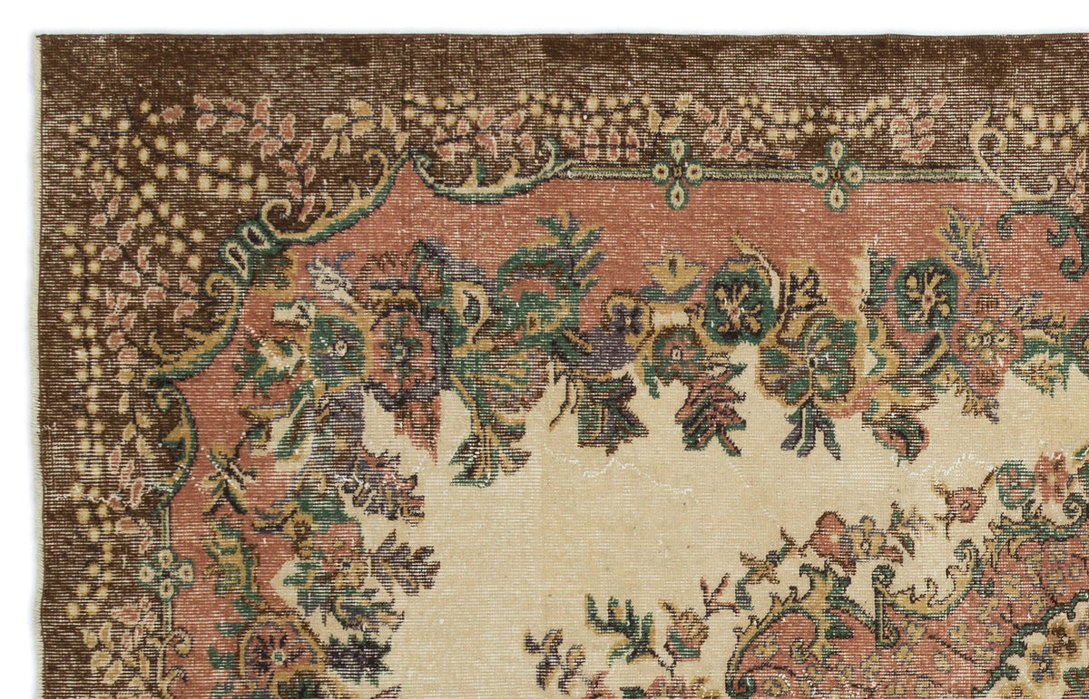 Vintage-style rug with a brown border, floral medallion pattern, and muted green, pink, and cream tones.