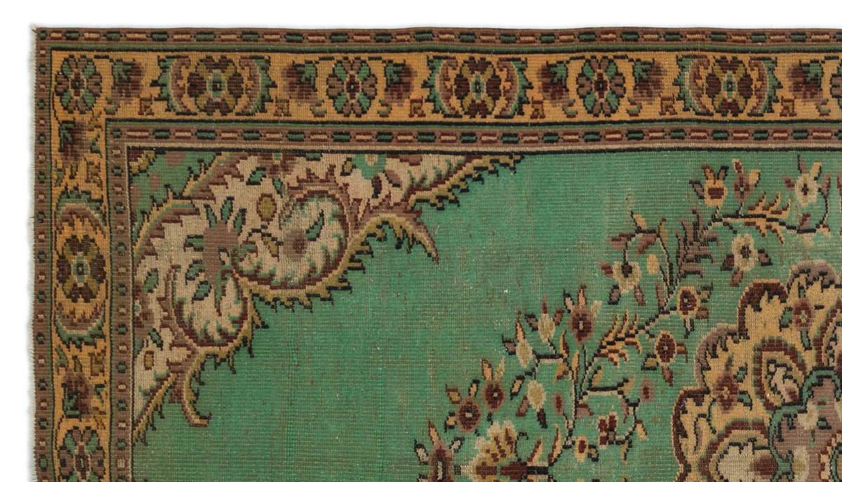 Green traditional rug with a tan floral border and intricate brown and beige paisley-style corner motifs.